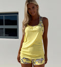 Woman wearing a yellow tank top and shorts with a white background