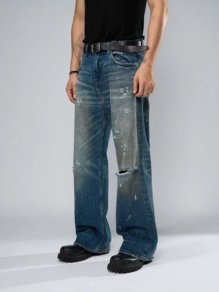 Person wearing distressed blue jeans on a plain background