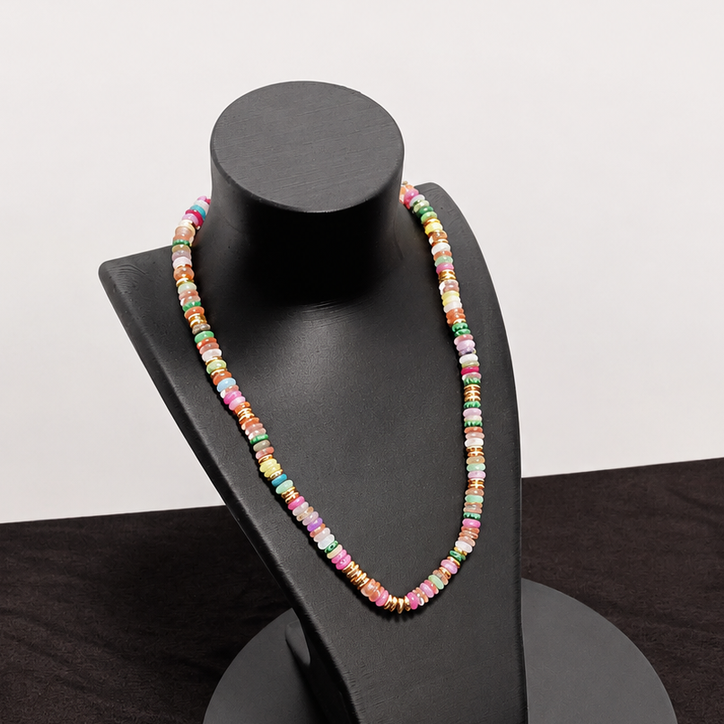 Colorful beaded necklace on a black jewelry stand against a dark fabric background