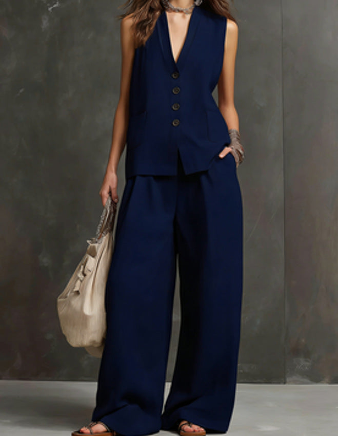 Person wearing a navy blue suit with wide-leg pants against a gray background