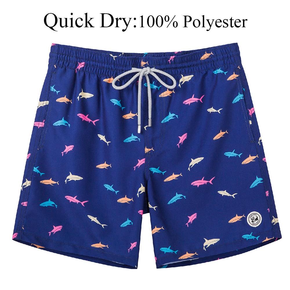 Blue swim shorts with shark pattern and quick dry text on a white background