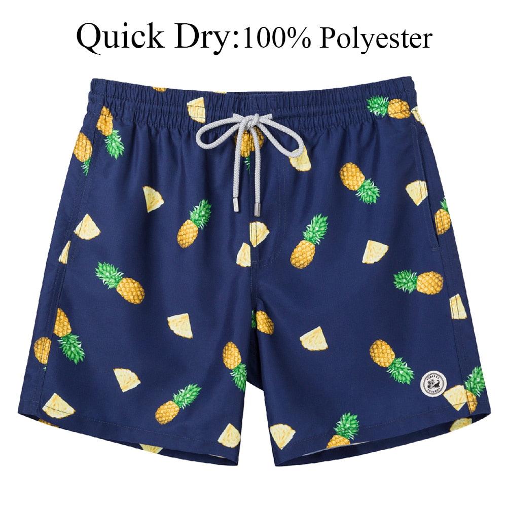 Navy blue swim shorts with pineapple pattern on a white background