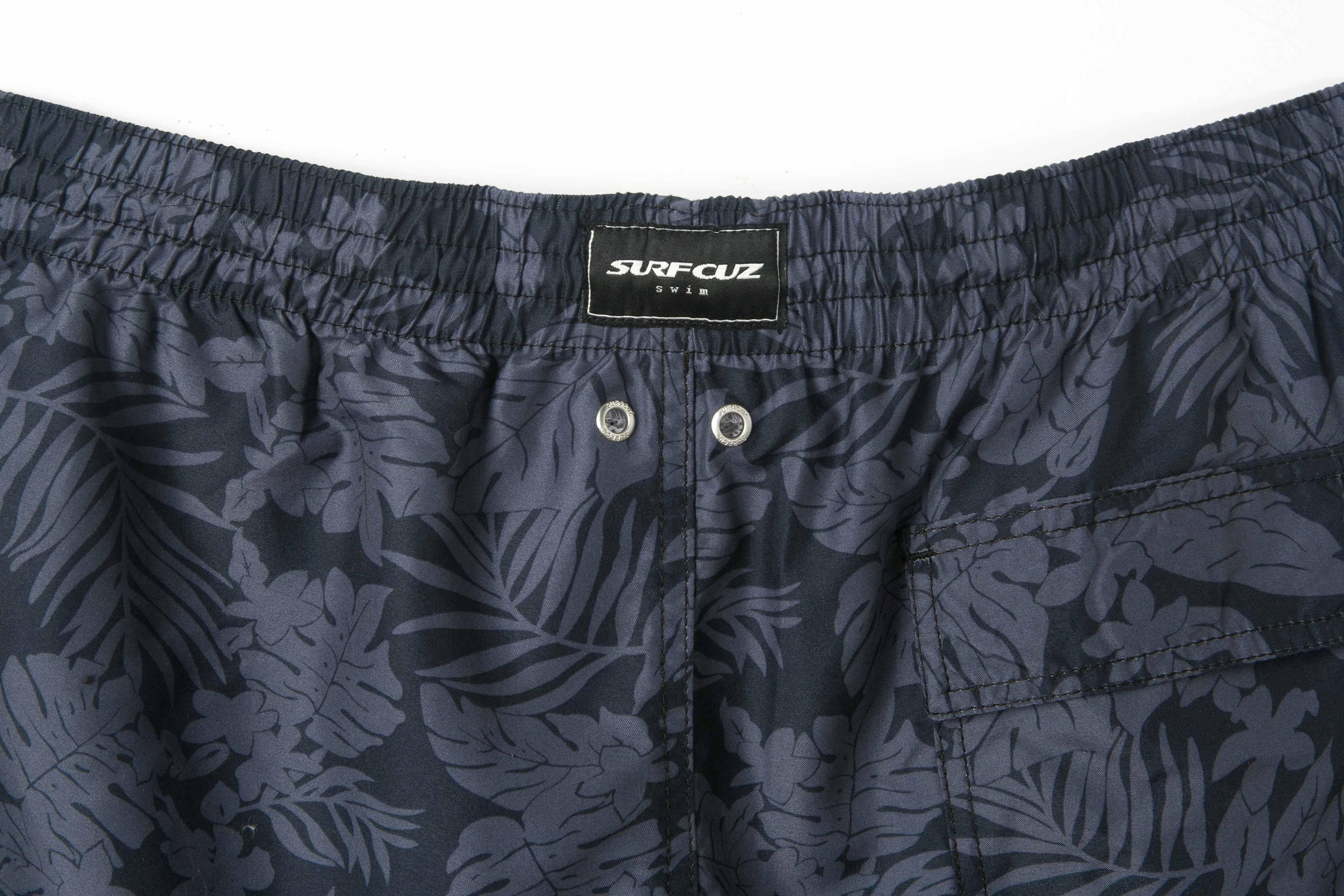 Navy blue swim shorts with leaf pattern and Surf Club label on a white background