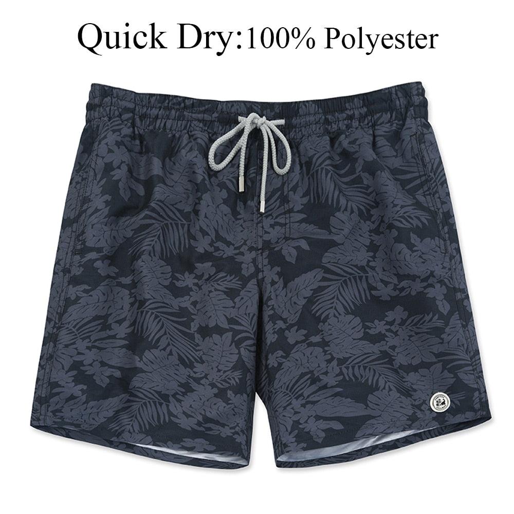 Dark patterned shorts with a drawstring on a white background, labeled 'Quick Dry: 100% Polyester'.