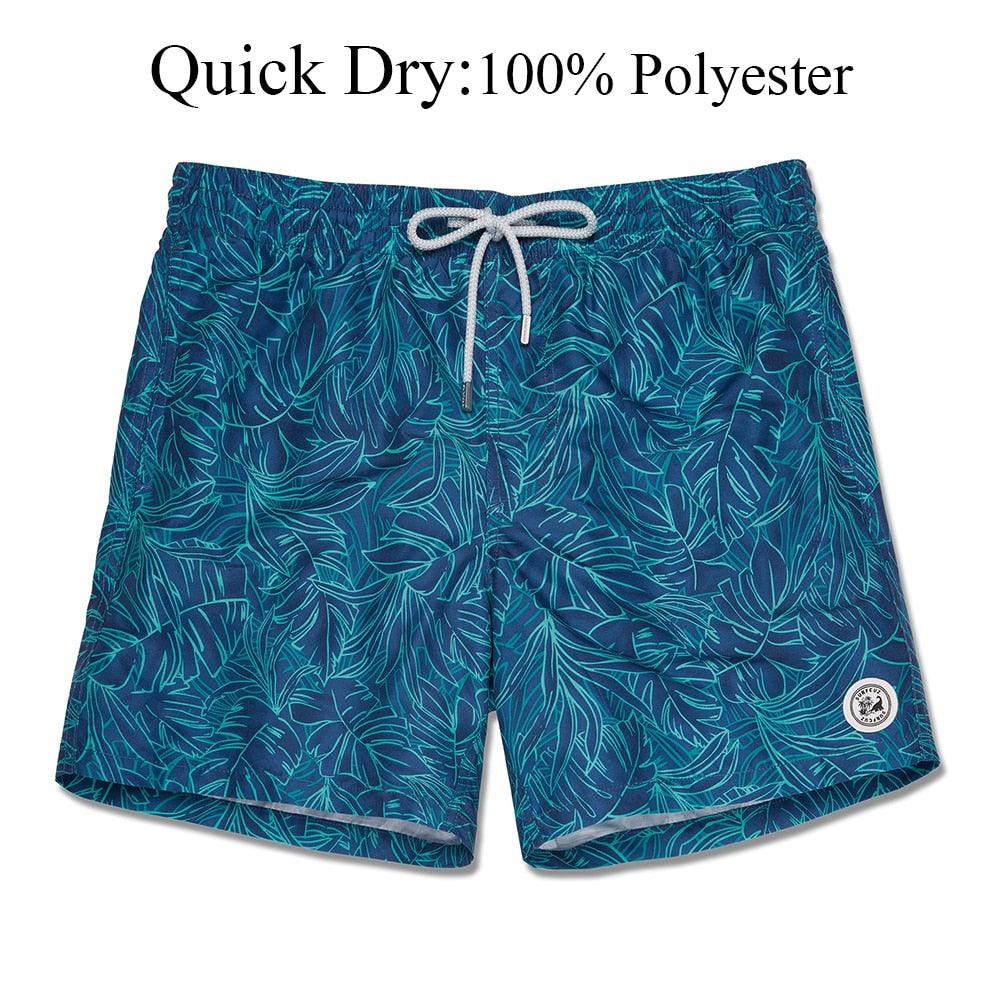 Blue leaf-patterned swim shorts with a drawstring on a white background, labeled as quick-dry and 100% polyester.