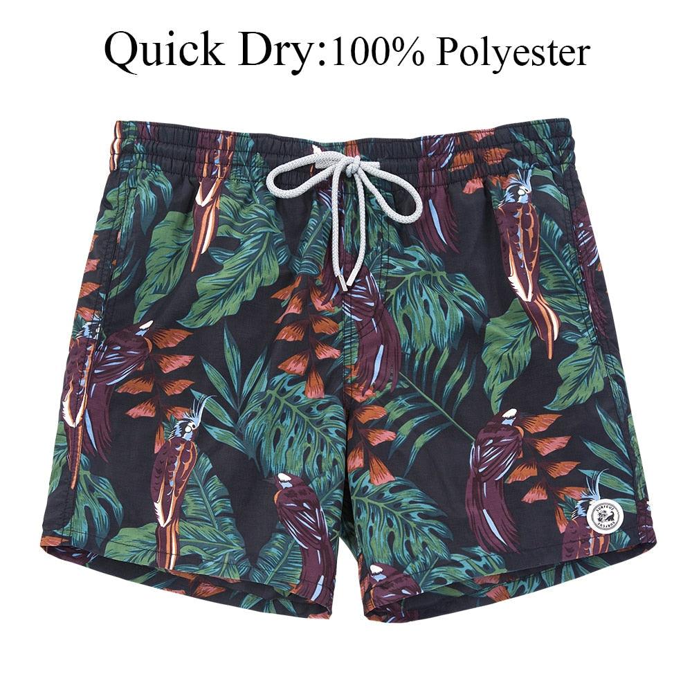 Tropical leaf patterned shorts with a drawstring on a white background, labeled 'Quick Dry: 100% Polyester'.